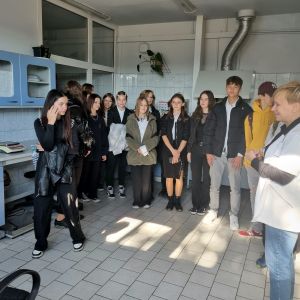 Grupa młodzieży stoi w półokręgu w jasnym pomieszczeniu