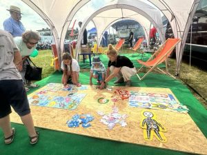 Dzieci wraz z dorosłymi układają kolorowe puzzle