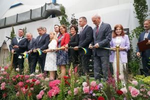 Grupa mężczyzn i kobiet na scenie przecina niebiesko - żółtą wstęgę