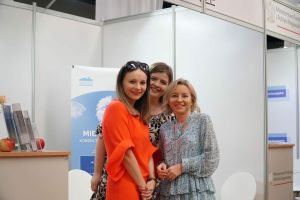 Trzy młode kolorowo ubrane kobiety stoja na stoisku