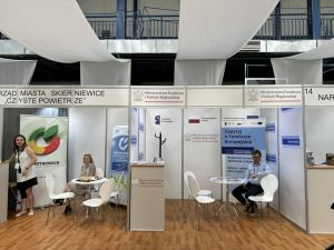 Stoiska targowe w kolorach białym, niebieskim i zielonym wraz  z nazwami firm na frezach.