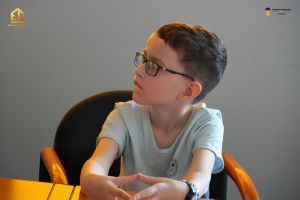 Zdjęcie siedzącego chłopca w sali konferencyjnej